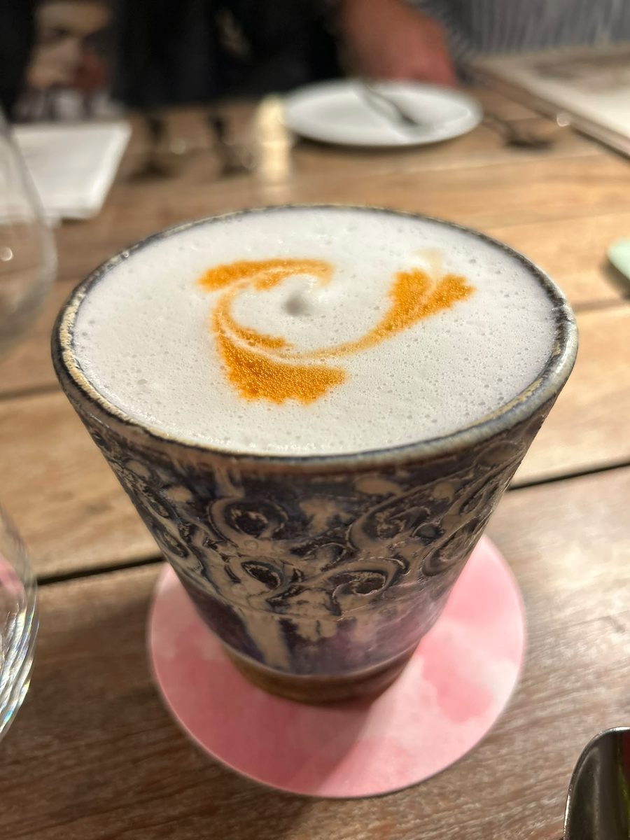 A pisco sour with decorated foam in a ceramic cup